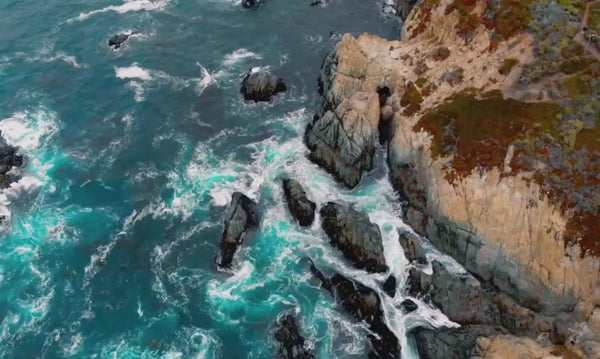 Vidéo de drone qui surplombe la mer avec des falaises et laisse apparaitre le logo IUM et son slogan