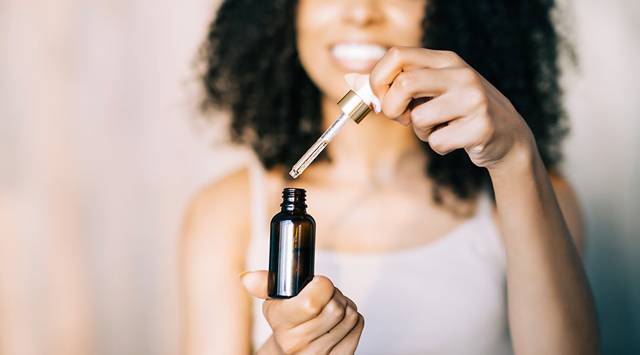 femme métisse utilise un sérum de soin cosmétiques