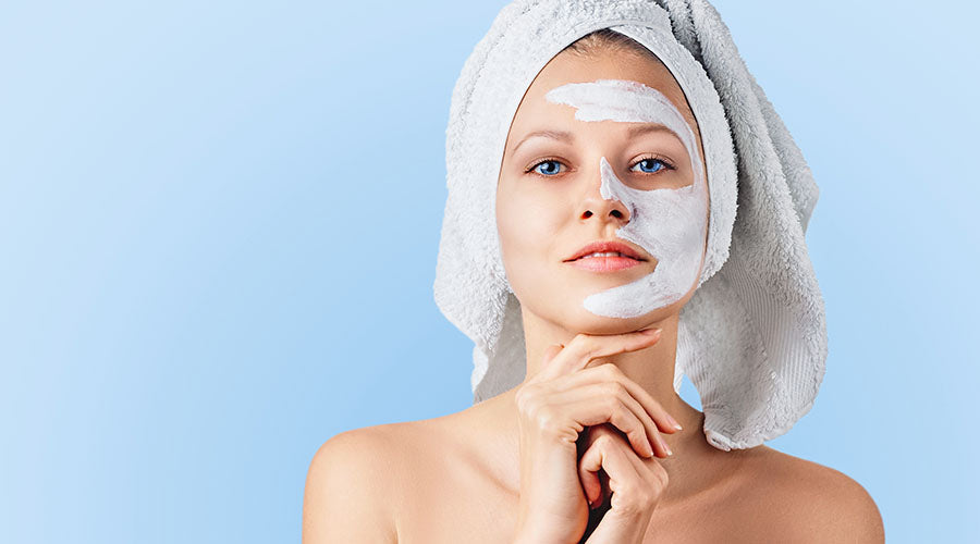 Femme avec un masque de soin visage naturel, serviette sur la tête, profitant d'un moment bien-être. Cosmétique bio enrichi en silicium pour une peau éclatante et revitalisée.