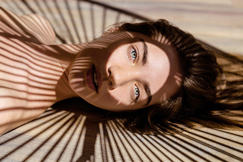 Femme à l'ombre, allongée à l'extérieur avec lumière uniquement sur ces yeux après un soin anti cernes ium paris