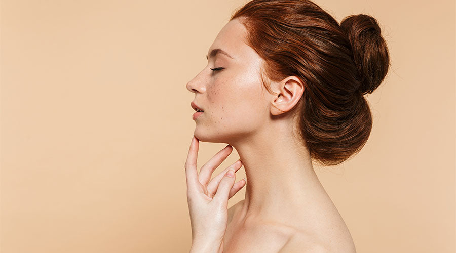 Visage jolie femme rousse de profil sur fond beige avec une belle peau 