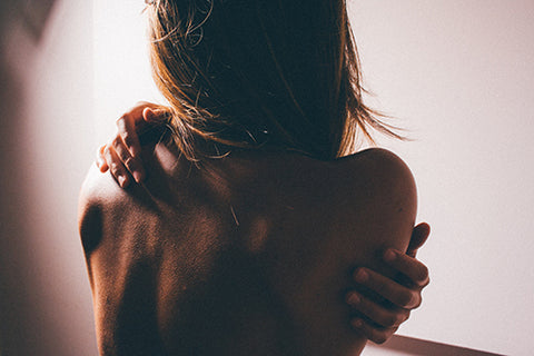 jeune femme de dos se masse les épaules