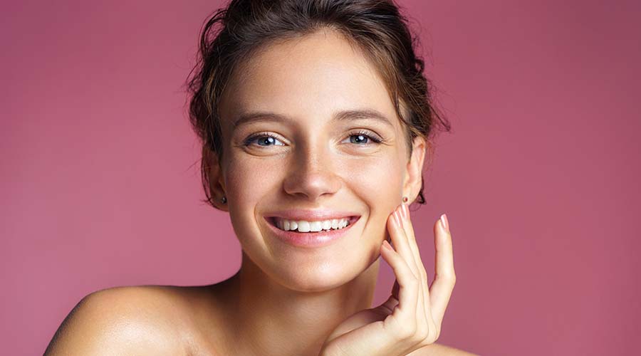 Visage d'un belle femme brune la quarantaine souriante sur fond pourpre