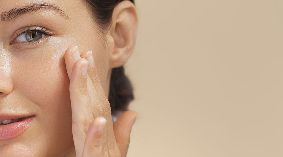 zoom visage femme brune qui se touche le visage sur fond beige