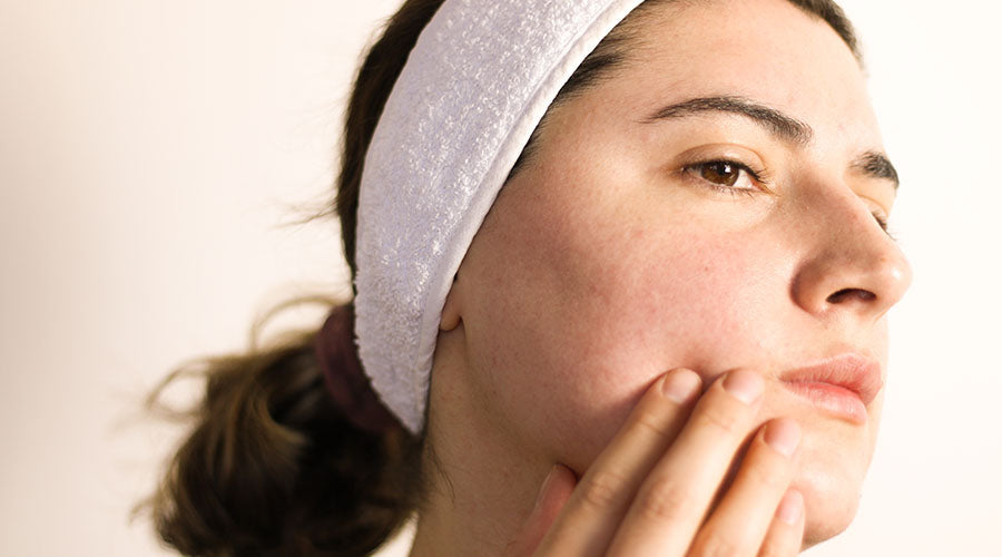 femme brune de profil qui se touche la peau du visage avec des rougeurs et une rosacée