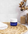 Pot bleu de masque gommage ium dans salle de bain lumineuse avec accessoires de couleur beige