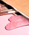 Pierre de massage Gua Sha en Quartz rose dépasse d'une trousse de maquillage