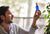 Homme tenant flacon bleu ium sur fond beige et plantes
